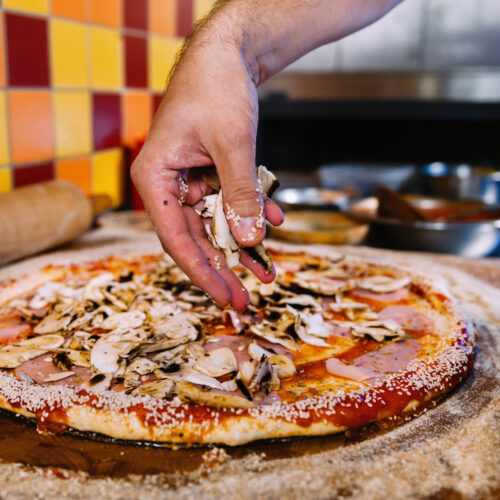 Putting mushrooms on pizza in pizza restaurant Moreton Bay region